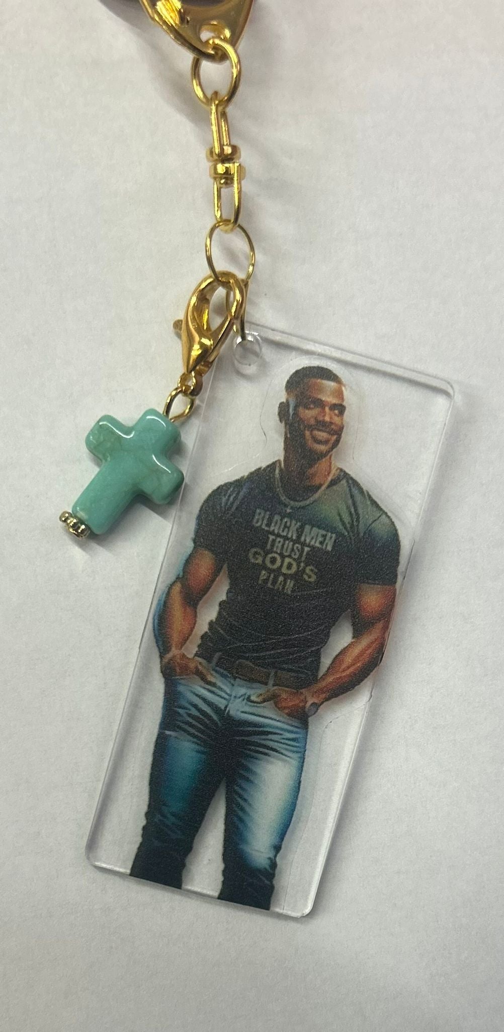 Sleutelhanger Real Men Pray van Onlyheknows2025, luxe ontwerp met gouden ring en turquoise kroonbedel, afgebeeld met een stijlvolle man in een shirt met de tekst 'BLACK MEN TRUST GOD'S PLAN'. Een elegant en betekenisvol accessoire voor moderne mannen.