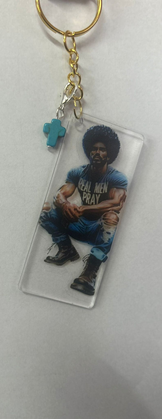 Elegante sleutelhanger 'Real Men Pray' van Onlyheknows2025, met een turquoise kruis en afbeelding van een stijlvolle man, symboliserend kracht en geloof in een luxe ontwerp.