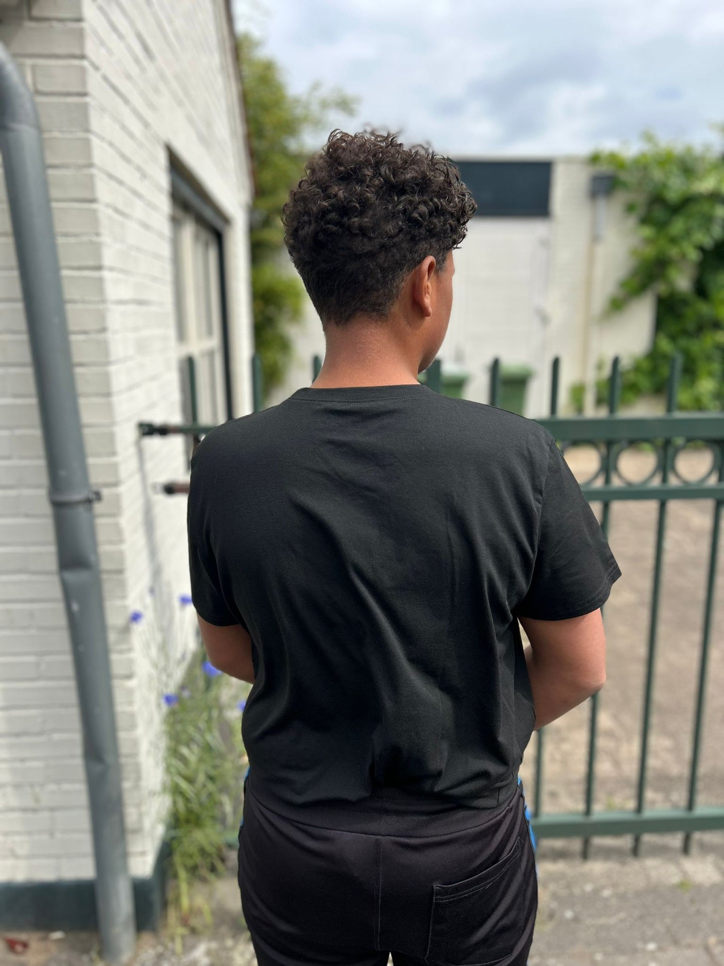 Achteraanzicht van een jongen die de Jesus Is King T-Shirt van Onlyheknows2025 draagt, benadrukt de luxe uitstraling en veelzijdigheid van het shirt in casual omgevingen.