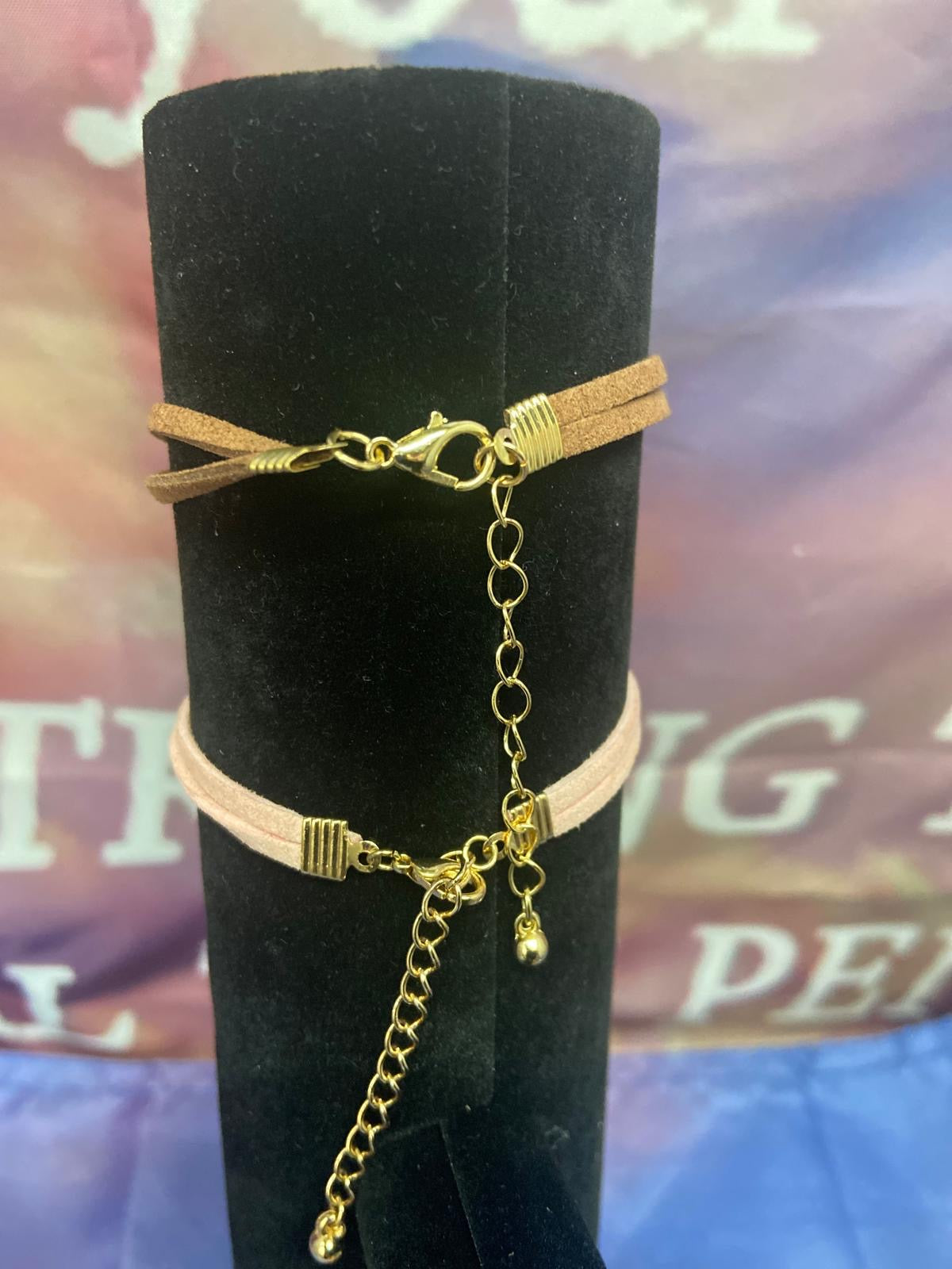 Dames Armband – Leren Band met Gouden Kruis (4 cm) - close-up van het gouden kruis op de zwarte leren band, een symbool van geloof en stijl.
