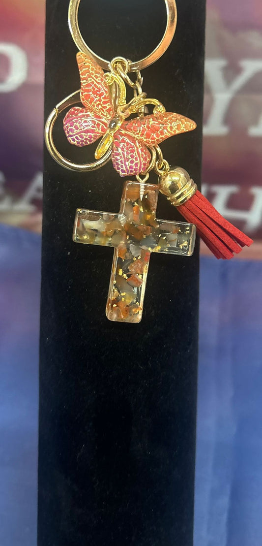 Faith in Bloom – Vlinder & Kruis Sleutelhanger in goudroze met een vlinderdetail, een gouden kruis en roze steenaccenten, perfect voor sleutels of als inspirerend cadeau.