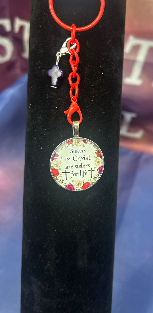 Elegante Sleutelhanger 'Sisters In Christ' van Onlyheknows2025, met een luxe ontwerp en een inscriptie die zegt: "Sisters in Christ are sisters for life", omgeven door delicate florale accenten.